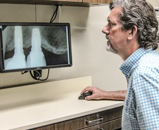 Dr. Thompson reviewing an x-ray of two dental implants on the monitor.